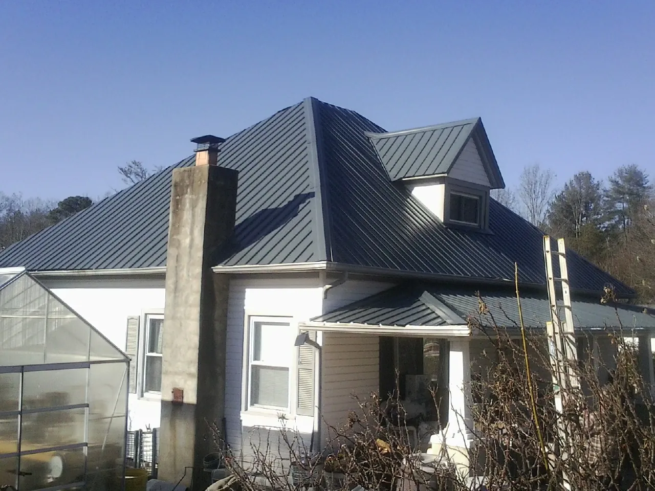Dark blue standing seam metal roof on a white farmhouse with dormer — Slate & Tile Roof Repair by Roofing Brothers in Dighton