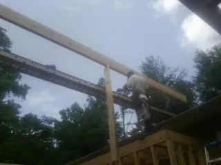Carpenter setting a ridge beam over a new addition frame — Ice Dam Removal by Roofing Brothers in Dighton