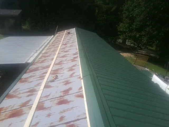 Old rusted panels beside newly installed green metal roofing — Wind Damage Roof Repair by Roofing Brothers in Dighton