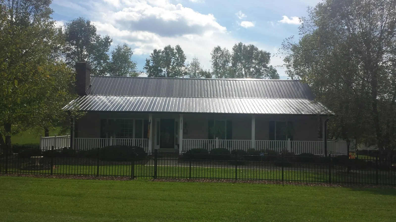 Gray metal roof on a brick ranch with a full width front porch — Gutter Guard Installation work by our crew in Dighton