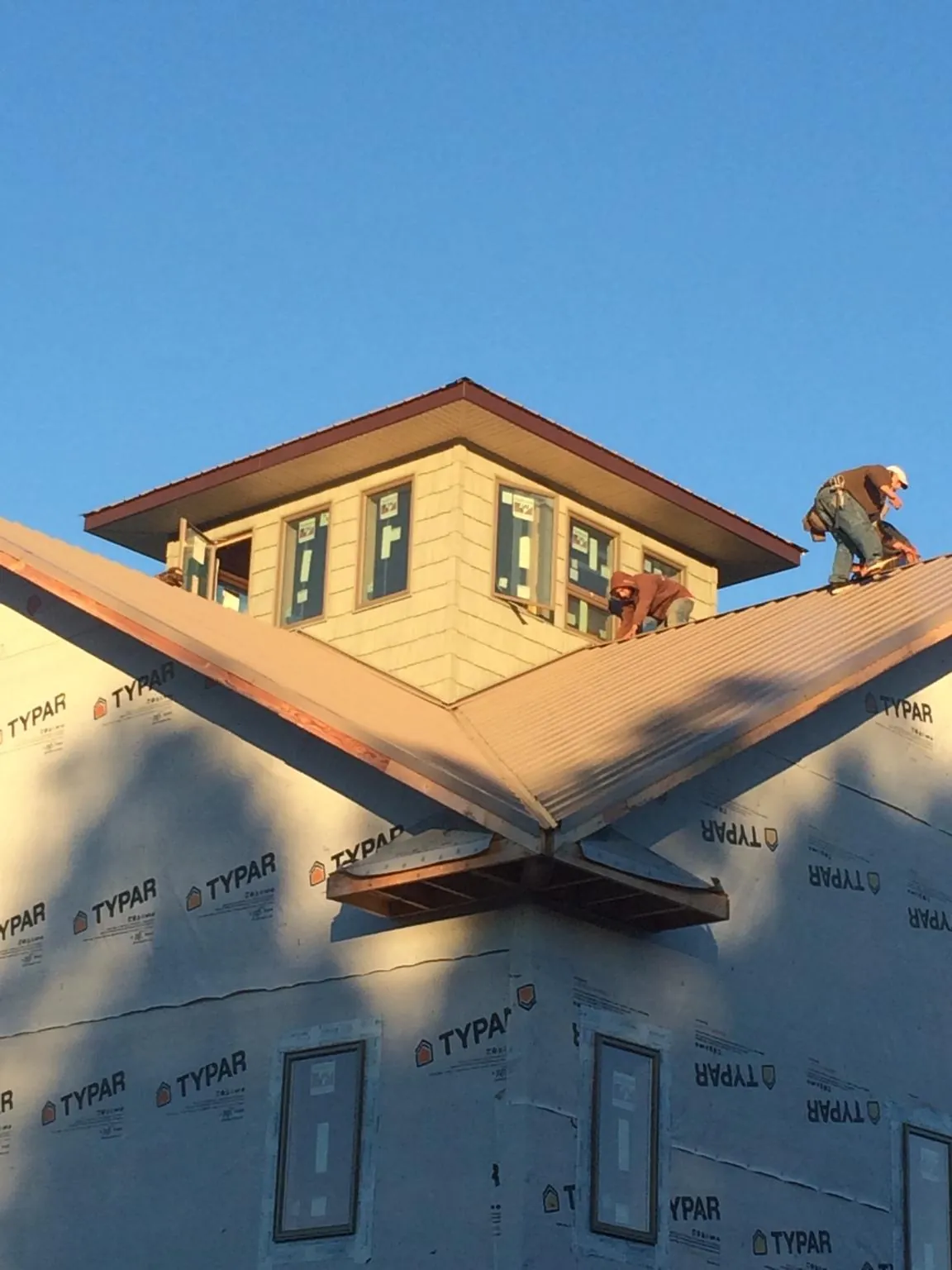 Roofers working around a rooftop cupola on a new metal roof at sunset — Roof Waterproofing in Dighton by Roofing Brothers